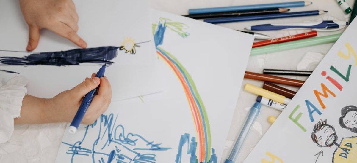 Children drawing with colorful markers on paper, depicting family and creativity.