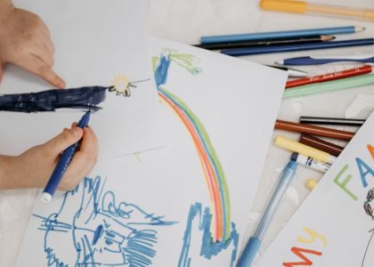 Children drawing with colorful markers on paper, depicting family and creativity.