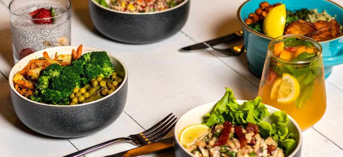 A vibrant assortment of healthy bowls and drinks showcasing fresh ingredients like broccoli and citrus.