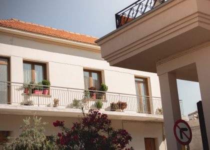 Traditional Greek house facade with potted plants and balcony details.